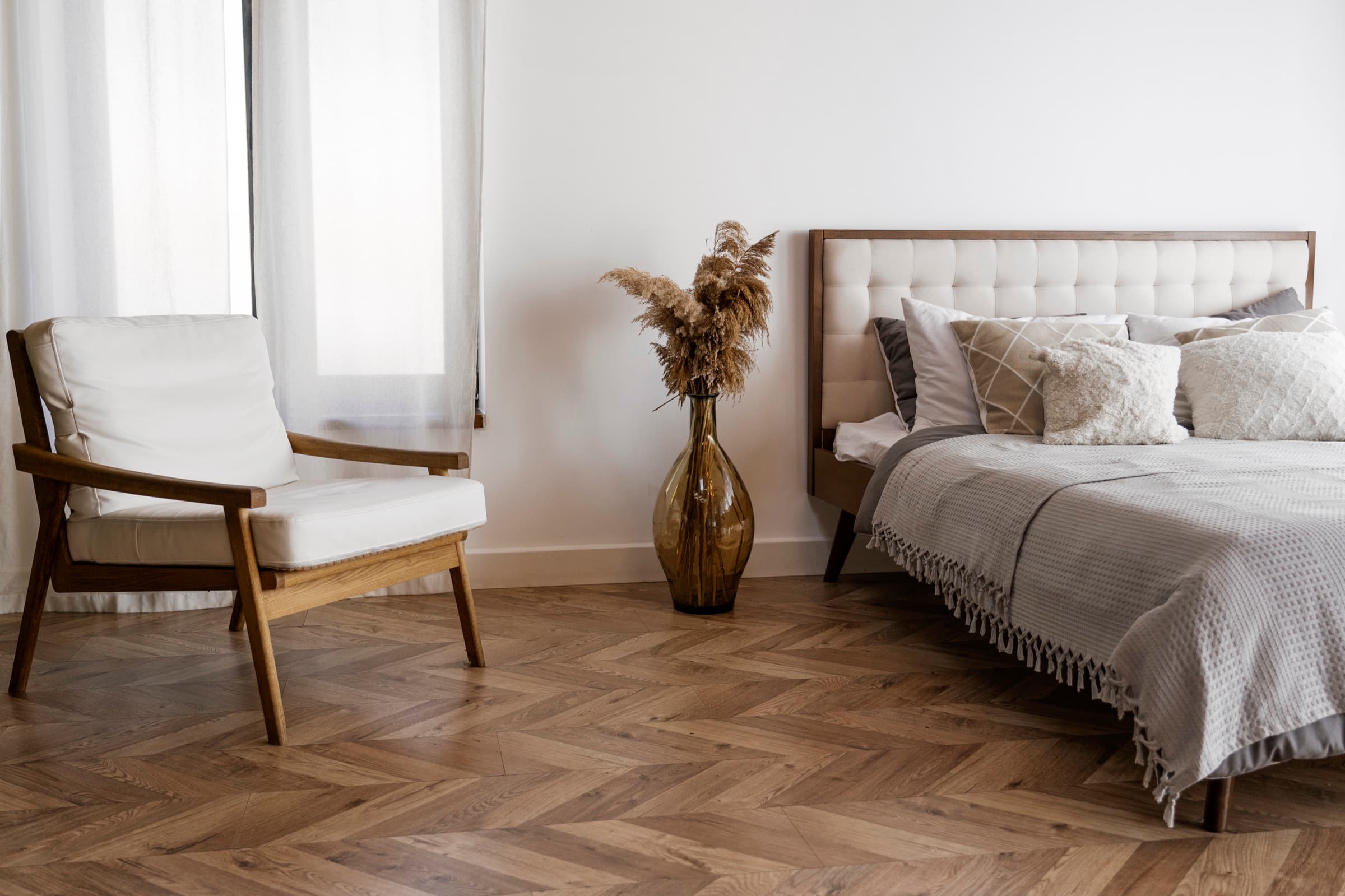 Timeless interior design: bedroom with herringbone timber flooring and a mid-century armchair
